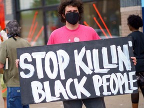 A man holds a 'Stop Killing Black People"" placard while protesting near the area where a Minneapolis Police Department officer allegedly killed George Floyd, on May 26, 2020 in Minneapolis, Minnesota.