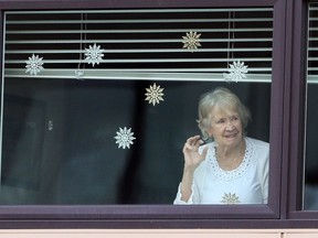 Residents wave to family members who created a Mother's Day parade of cars for their moms and grandmothers at the Amica Britannia seniors residence in Calgary, May 10, 2020.