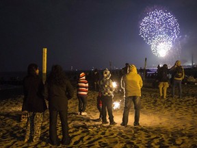 A family watches the Victoria Day fireworks on the beach in Toronto on Monday, May 20, 2013.