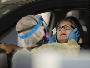 From the comfort of her vehicle, Patricia Zurczak gets tested for COVID-19 by an EMS paramedic at a drive-thru location in the SilverCity Windsor Cinemas parking lot on Friday, May 29, 2020.