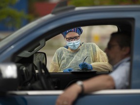 A nurse practitioner with the Windsor/Essex County Health Unit records the health information of a man waiting in line for a COVID-19 test at a drive-thru location in the SilverCity Windsor Cinemas parking lot, Friday, May 29, 2020.