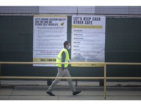 A Chrysler employee walks past COVID-19 safety recommendations posted outside Windsor Assembly Plant, Tuesday, May 12, 2020.