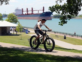 Windsor, Ontario. June 15, 2020. An unidentified cyclist rides his mountain bike along the Windsor riverfront at Askin Boulevard where a Celestrial Beacon is proposed Monday.  The beacon will house the Windsor's amazing Streetcar No. 351 if the location for the project is approved.