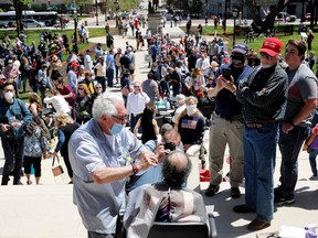 Barber Karl Manke of Owosso cuts hair at the Michigan Conservative Coalition organized "Operation Haircut" outside the Michigan State Capitol in Lansing, Michigan on May 20, 2020. - The group is protesting Michigan Governor Gretchen Whitmer's mandatory closure to curtail the coronavirus pandemic.