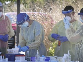 Health-care workers are shown during a busy day at the COVID-19 drive-through testing site at the Atlas Tube Centre in Lakeshore, on Friday.