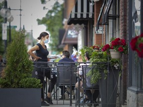 A waitress works on the patio at Vito's Pizzeria on the first day of patios reopening since the COVID-19 pandemic began, Thursday, June 25, 2020.