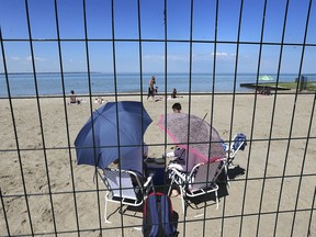 A small group of sunbathers are shown at a fenced off and closed section of Sandpoint Beach in Windsor on Tuesday, June 30, 2020.