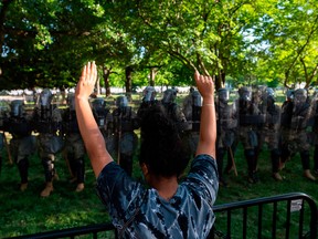 A protester raises her hands near a line of U.S. National Guard soldiers deployed near the White House on June 1, 2020, as demonstrations against George Floyd's death continue.
