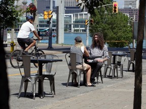 Thyme Kitchen customers Neira Hoso, seated left, and Eric Adams on Ouellette Avenue Wednesday morning.  Both lanes of traffic on Ouellette Avenue were detoured as businesses were allowed to expand their seating onto the pavement.