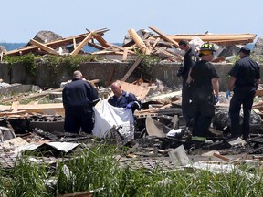 Body removal specialists, Leamington firefighters and Ontario fire investigators prepare to remove one of the deceased Monday, following an explosion and fire on Marentette Beach. Two people were found dead at the scene.