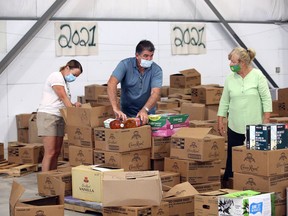 June 27th Miracle volunteer Nancy Campana, left, assists Dan and Marie Inverarity, right, who were selecting food items to be delivered to quarantined migrant farm workers Thursday. LaSalle Miracle Food Drive opened the doors of Westport Marina in LaSalle Thursday for laid off employees at Caesars Windsor and those in the Event/Wedding industry and other businesses closed long term due to the COVID pandemic.