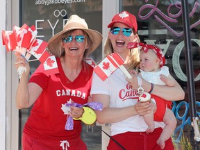 Jill Jakob, left, her daughter Dr. Abby Jakob and granddaughter Max Michaud, 5 months old, hand out Canada cupcakes on Main Street East in Kingsville Tuesday.