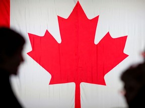 People are silhouetted in front of the Canadian national flag at the Palais des Congres in Montreal, Oct. 21, 2019.