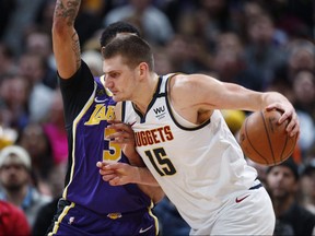 In this Feb. 12, 2020, file photo, Denver Nuggets centre Nikola Jokic drives as Los Angeles Lakers forward Anthony Davis defends in Denver.