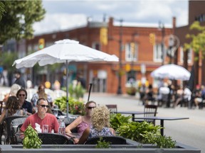 People enjoy food and drinks on patios set up on the road on the first day of Kingsville's Open Streets, Saturday, July 11, 2020.