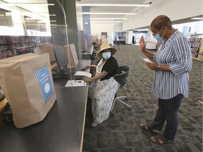Cautiously reopening, the central branch of the Windsor Public Library on Ouellette Ave. opened its doors for public computer use on Monday, July 27, 2020. Social distancing measures are in place. Here, a client, left, receives help from Wendy Nancoo, a public services librarian.