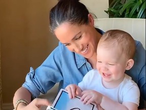 This handout image released on May 6, 2020, on the @SaveChildrenUK Instagram account of the charity Save the Children, and taken from a video filmed in California by Britain's Prince Harry, Duke of Sussex, shows Meghan, Duchess of Sussex reading from the book Duck! Rabbit! to their son Archie, on his first birthday.