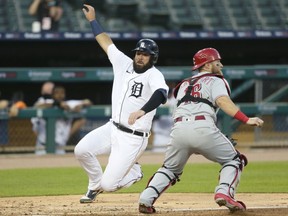 Austin Romine of the Detroit Tigers scores past catcher Tucker Barnhart #16 of the Cincinnati Reds on a hit by JaCoby Jones during the fifth inning at Comerica Park on July 31, 2020, in Detroit, Michigan.