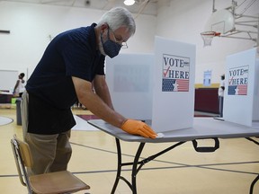 A poll worker sanitizes a voting area at Keevan Elementary School August 4, 2020 in  St. Louis, Missouri. Primary voters in Arizona, Kansas, Michigan, Missouri and Washington state go to the polls today amid safety precautions due to the coronavirus pandemic.