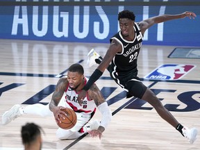 Damian Lillard #0 of the Portland Trail Blazers falls while chasing the ball against Caris LeVert #22 of the Brooklyn Nets in the second half at AdventHealth Arena at ESPN Wide World Of Sports Complex on August 13, 2020 in Lake Buena Vista, Florida.