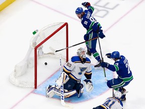 Canucks winger Antoine Roussel (right) celebrates after his second-period goal with linemate Adam Gaudette (top) against St. Louis Blues goalie Jordan Binnington in Game 6 of their NHL Western Conference first-round playoff series at Rogers Place in Edmonton on Aug. 21, 2020.