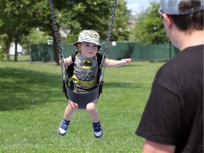Maddox Munoz, 1, flies like Batman while on the swings with his father Eric Munoz at Lanspeary Park Monday.