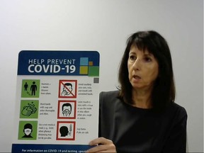 Windsor-Essex County Health Unit CEO Theresa Marentette holds up  signage created by WECHU for municipal facilities to help prevent the spread of COVID-19 during a virtual news conference on Thursday, Aug. 13, 2020.