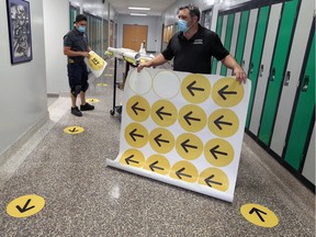 This way and that way. Custodians James Pomponio, left, and Ron Galipeau, both with Greater Essex County District School Board, apply directional and distancing stickers to floors at W. F. Herman Academy on Tuesday, Aug. 25, 2020.