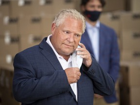 Ontario Premier Doug Ford removes a disposable mask as he approaches the podium during an announcement on N95 masks at a facility in Brockville, Ont., Friday, Aug. 21, 2020.