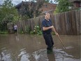 Windsor's newest river in the core: Tom Klaras tries to help drain a flooded alley behind his home on Bruce Avenue on Friday, August 28, 2020.