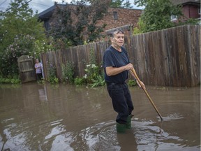 Windsor's newest river in the core: Tom Klaras tries to help drain a flooded alley behind his home on Bruce Avenue on Friday, August 28, 2020.