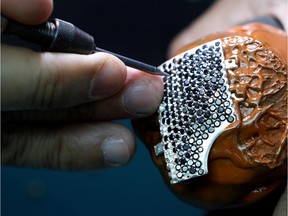 A diamond's setter works on a part of a protective coronavirus disease (COVID-19) gold face mask in a fine jewelry factory in Motza, Israel, August 11, 2020.