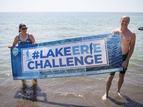 Kirsten Poling, left, and Dennis Higgs, hold up a Lake Erie Challenge sign after Higgs finished his swim from Colchester Beach to Cedar Beach for the Lake Erie Challenge, Saturday, August 22, 2020.