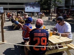 Edmonton Oilers' fans watch the first game of the Oilers series with the Chicago Blackhawks from the patio at Campio Brewing Co. in Edmonton Saturday, Aug. 1, 2020.