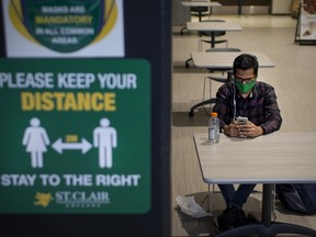 Mahammadabrar Vohra, a student at St. Clair College, sits in the common area where social distancing and COVID-19 guidelines are posted, Wednesday, August 19, 2020.