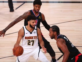 Denver Nuggets guard Jamal Murray, left, handles the ball while Los Angeles Clippers guard Paul George and forward Kawhi Leonard, right, during the first half in game seven of the second round of the 2020 NBA Playoffs at ESPN Wide World of Sports Complex, Sept. 15, 2020.