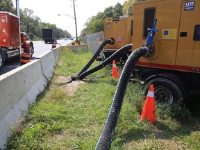 Tractor trailer rigs rumble past two, industrial pumps at the site of a sanitary sewer collapse on Ojibway Parkway Wednesday.