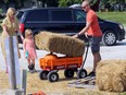 Jason Laughland, right, daughter Rosie, 4, and wife Barbara Herbster-Laughland, left, carefully pull a bale of straw and pumpkins at PéPé's Pumpkin Patch and hay ride on Front Road Thursday.