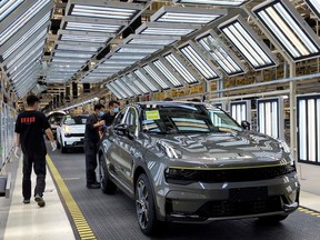 FILE PHOTO: Employees wearing face masks following the coronavirus disease (COVID-19) outbreak work on a Lynk & Co car production line at Geely's Yuyao plant in Ningbo city, Zhejiang province, China May 7, 2020.