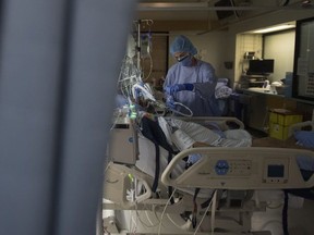 Registered nurse Liana Perruzza attends to a patient in a COVID positive room in the COVID-19 intensive care unit at St. Paul's hospital in downtown Vancouver, Tuesday, April 21, 2020.