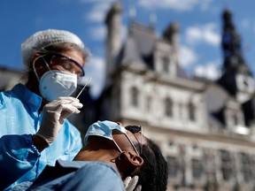FILE PHOTO: A health worker, wearing a protective suit and a face mask, prepares to administer a nasal swab to a patient at a testing site for the coronavirus disease (COVID-19) installed in front of the city hall in Paris, France, September 2, 2020.
