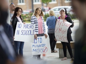 Protesters opposed to wearing masks rally outside city hall during a city council meeting, Monday, September 28, 2020.