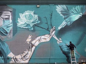 David (DERKZ) Derkatz puts the finishing touches on his mural on the side of the Windsor's Penalty Box Restaurant on Walker Road, Tuesday, September 29, 2020.  The mural is a tribute to medical front-line workers.