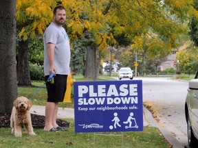 Rob Guthrie and pet Nash watch for speeding traffic outside their home on Avondale Avenue Thanksgiving Day.  The Guthries recently erected a new City of Windsor sign that urges motorists to slow down.