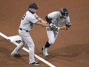 Giancarlo Stanton of the New York Yankees is congratulated by third base coach Phil Nevin after hitting a three run home run against the Tampa Bay Rays during the fourth inning in Game Two of the American League Division Series at PETCO Park on October 06, 2020 in San Diego, California.