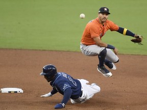 Carlos Correa of the Houston Astros turns a double play forcing out Yandy Diaz of the Tampa Bay Rays at second base during the sixth inning in Game Six of the American League Championship Series at PETCO Park on October 16, 2020 in San Diego, California.