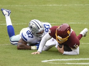 LANDOVER, MARYLAND - OCTOBER 25: Quarterback Kyle Allen #8 of the Washington Football Team is tackled by Everson Griffen #97 of the Dallas Cowboys in the first half of the game at FedExField on October 25, 2020 in Landover, Maryland.