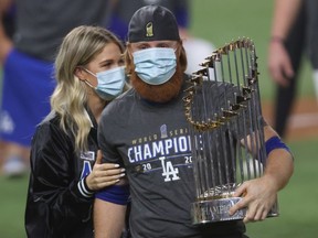 Justin Turner of the Los Angeles Dodgers and his wife Kourtney Pogue, hold the Commissioners Trophy after the teams 3-1 victory against the Tampa Bay Rays in Game Six to win the 2020 MLB World Series at Globe Life Field on October 27, 2020 in Arlington, Texas.