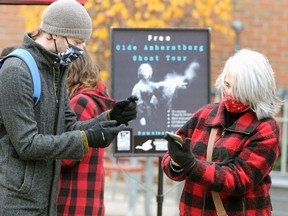 Tristan Tiggeloven, left, of On Foot Tours helps Lauri Brouyette download the app for the Olde Amherstburg Ghost Tour which was officially launched Thursday at King's Navy Yard Park.