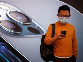 A man wears a face mask while waiting at an Apple Store before the new iPhone 12 goes on sale in Shanghai, China October 23, 2020.